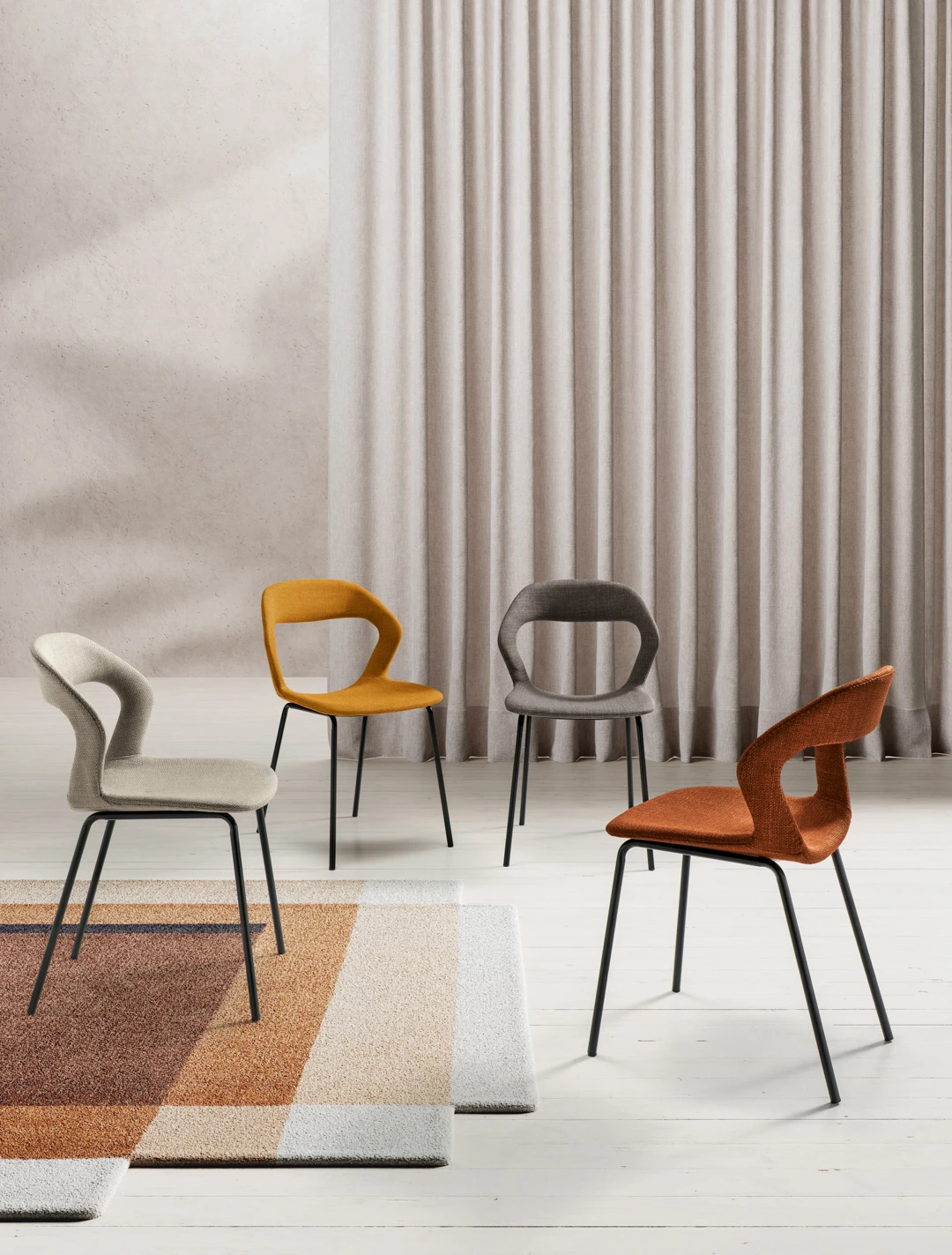 Sedia imbottita in tessuto Gilda con schienale forato e gambe in metallo nero, disponibile in più colori