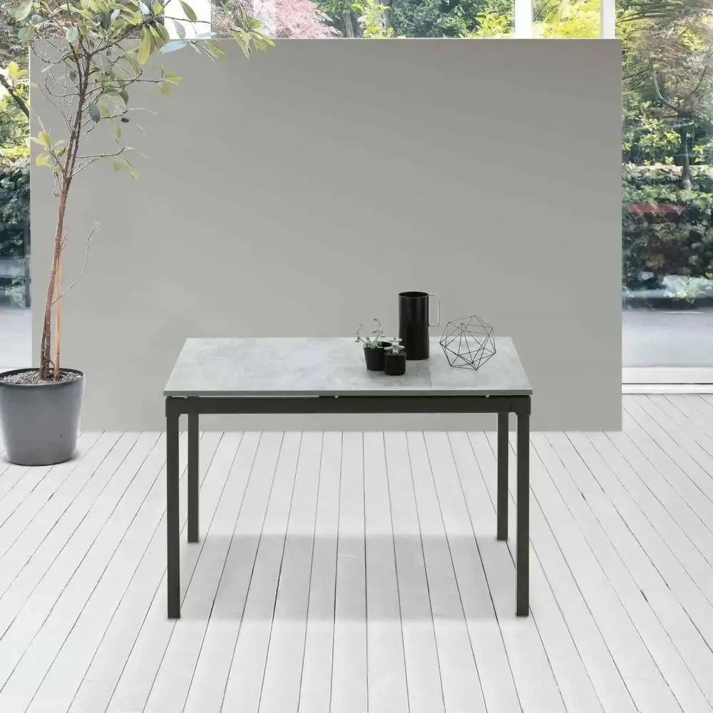 Tavolo allungabile 120x80 con struttura telescopica in metallo nero e piano in laminato effetto cemento chiaro Perigeo, mostrato in posizione chiusa in una zona living moderna.