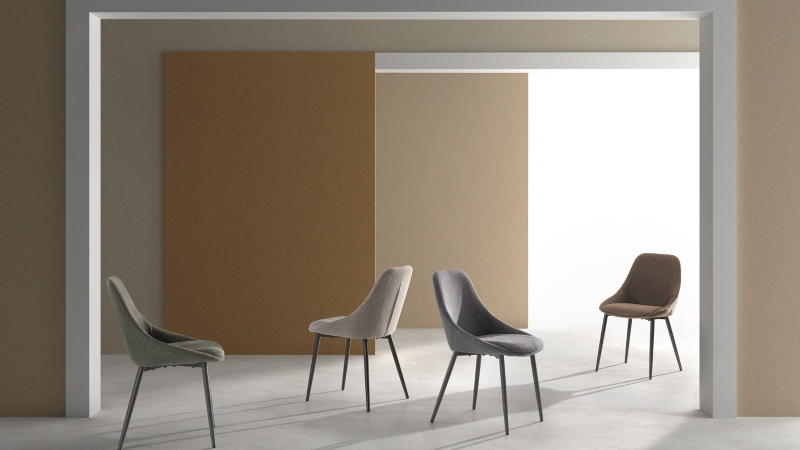 Quattro varianti della sedia Kira in tessuto easy-clean con rivestimenti in diverse tonalità e gambe in metallo verniciato in un ambiente dining moderno.